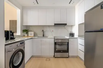 a kitchen with white cabinets and a washer at GuestReady - Charming haven at Binghatti Crest in Dubai