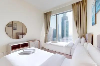 a hotel room with two beds and a mirror at Forte Tower 2 - Warm Two Bedroom in Dubai