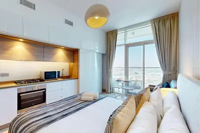 a living room with a large couch and a kitchen at Studio One - Gorgeous Studio in Dubai
