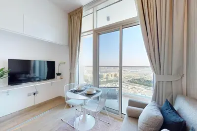 a living room with a table and a large window at Studio One - Gorgeous Studio in Dubai