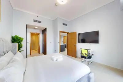 a white bedroom with a white bed and a tv at Ocean Heights - Exquisite One Bedroom in Dubai
