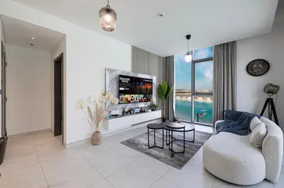 a white living room with a tv and a couch at Full Lagoon View Beach Access Exclusive building in Dubai