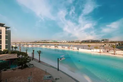 a large swimming pool next to a beach with palm trees at Full Lagoon View Beach Access Exclusive building in Dubai