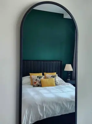 a bedroom with a large bed with a green wall at Alaia Retreat in Dubai
