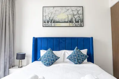 a bed with a blue headboard and two blue pillows at Elegant 1 bedroom in Creek Edge in Dubai