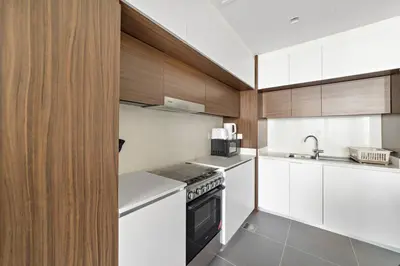 a kitchen with white appliances and wooden cabinets at Elegant 1 bedroom in Creek Edge in Dubai