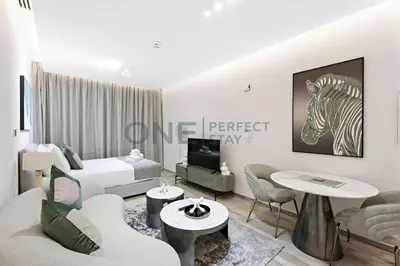 a white living room with a bed and a living room with at Studio Chic In Business Bay With Pool and Gym in Dubai