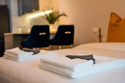 a pile of towels on a bed with two chairs at Spacious Luxe Studio Near Metro in Dubai