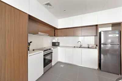 a kitchen with white cabinets and a stainless steel refrigerator at Elegant 1 bedroom in Creek Edge in Dubai