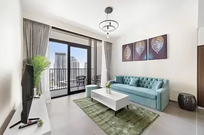 a living room with a blue couch and a large window at Elegant 1 bedroom in Creek Edge in Dubai
