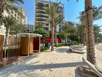 a sandy beach with palm trees and lounge chairs at Elegant at Creek Beach 1 BHK in Dubai