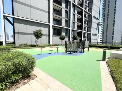 a green lawn in front of a building at Stylish 1 Bedroom High Floor in Creek Edge in Dubai