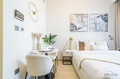 a bedroom with a bed and a table and a chair at Alluring Studio Apartment at Azizi Riviera 16, Al Merkadh by Deluxe Holiday Homes in Dubai