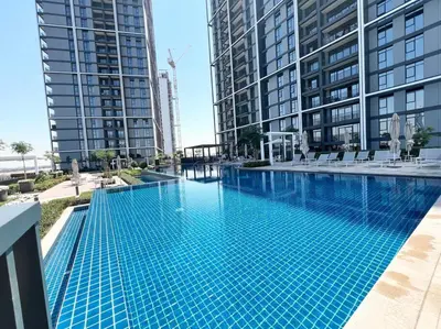 a swimming pool in the middle of two tall buildings at Stylish 1 Bedroom High Floor in Creek Edge in Dubai