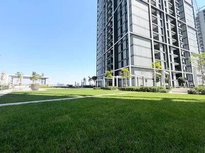 a large building with a green lawn in front of it at Stylish 1 Bedroom High Floor in Creek Edge in Dubai