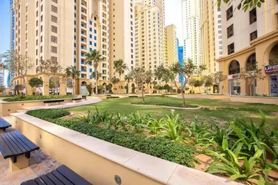 a park in the middle of a city with tall buildings at Prime Spacious Studio with Vibrant Vibes in JBR By SWEET HOMES in Dubai