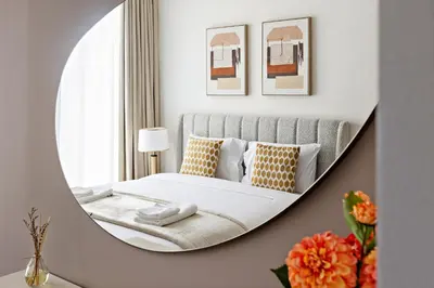 a round mirror in a bedroom with a bed at Chic 1-Bed Near Marina Promenade - 5 min to Tram in Dubai