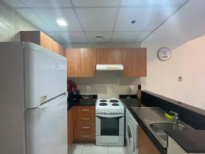 a kitchen with a white refrigerator and a stove at Very Convenient Apartment steps to Metro and Marina Mall Managed by SunnyHomes in Dubai