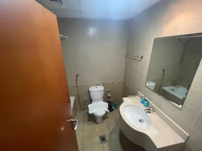 a bathroom with a toilet and a sink and a mirror at Very Convenient Apartment steps to Metro and Marina Mall Managed by SunnyHomes in Dubai
