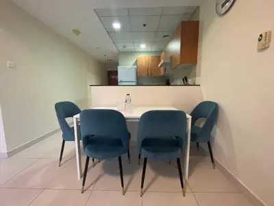 a dining room with a table and blue chairs at Very Convenient Apartment steps to Metro and Marina Mall Managed by SunnyHomes in Dubai