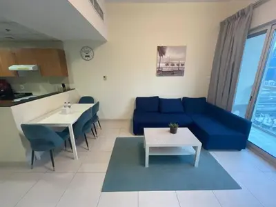 a living room with a blue couch and a table at Very Convenient Apartment steps to Metro and Marina Mall Managed by SunnyHomes in Dubai