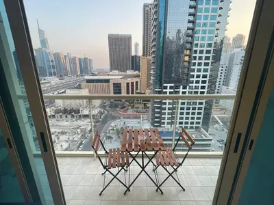 two chairs on a balcony with a view of a city at Very Convenient Apartment steps to Metro and Marina Mall Managed by SunnyHomes in Dubai