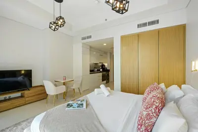 a hotel room with a white bed and a television at Stylish Studio with Great Views High Floor in Dubai