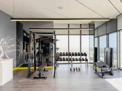 a gym with rows of exercise equipment and windows at Stylish Studio with Great Views High Floor in Dubai