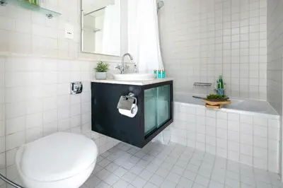a white tiled bathroom with a toilet and a sink at Frank Porter - Al Majara Tower 2 in Dubai