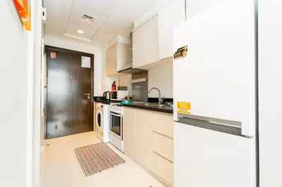 a kitchen with white cabinets and a refrigerator at Sleek Studio in Damac Hills - Premium Living with Top-Class Amenities, Managed by Think Realty in Dubai