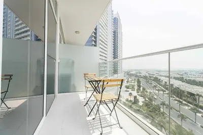 two chairs and a table on the balcony of a building at Golf View Studio in Damac Hills - Luxury Living, Exclusive Amenities, by Think Realty in Dubai