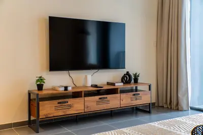 a living room with a television on a wall at SettlerHomes - Chic Creek Edge 1BR With Harbour View in Dubai