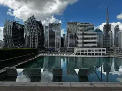 a city skyline with a swimming pool in front of a city at Cosy Studio on the Binghatti Canal in Dubai