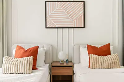 two white beds with orange pillows in a room at Silkhaus Large 3BR plus Maid Room Elegant Marina View in Dubai