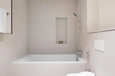 a white bathroom with a tub and a toilet at Silkhaus Large 3BR plus Maid Room Elegant Marina View in Dubai