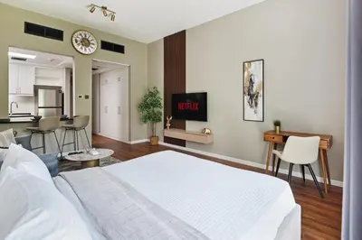 a bedroom with a white bed and a kitchen at Chic studio near metro at Discovery Gardens in Dubai