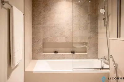 a bathroom with a bath tub with a glass door at New Stylish 1BR Apartment, Next to Dubai Mall - Downtown Views ll, Tower 3 in Dubai