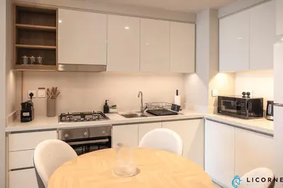 a kitchen with white cabinets and a table with chairs at Top Floor Urban Oasis Steps from Dubai Mall - 1BR Apartment in Downtown Views ll, Tower 1 in Dubai