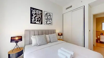 a bedroom with a large white bed and a lamp at Socio Tower 2 - Neat One Bedroom in Dubai