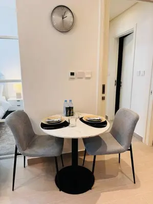 a dining room table with chairs and a clock on the wall at Golfville LighthouseDubai Hills in Dubai