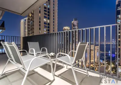 a balcony with chairs and a city skyline at night at Luxurious 2 BR- Dubai Creek Harbour - Host & Stay in Dubai
