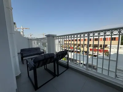 a balcony with two chairs and a view of a building at ASHRI Luxurious Apartment in Arjan near Miracle Gardens in Dubai