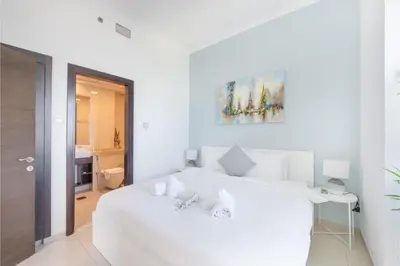 a white bedroom with a white bed and a bathroom at HAVN - 1 Bedroom in Dubai Marina with Sea Views in Dubai