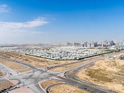 an aerial view of a highway with a city in the background at Studio in Damac Hills - Modern Comfort with Premium Amenities,by Think Realty in Dubai