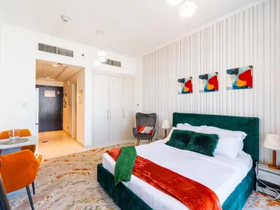 a bedroom with a large bed and a chair at Studio in Damac Hills - Modern Comfort with Premium Amenities,by Think Realty in Dubai