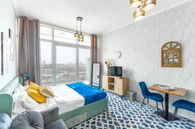 a bedroom with a bed and a desk and a window at Studio in Damac Hills - Luxurious Living with Premium Amenities, by Think Realty in Dubai