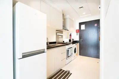 a kitchen with white cabinets and a black door at Studio in Damac Hills - Luxurious Living with Premium Amenities, by Think Realty in Dubai