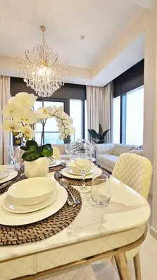 a dining room table with a chandelier and white plates at Luxury 3 bedroom Aykon Tower in Dubai