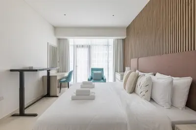 a bedroom with a large white bed and a desk at Palm Jumeirah 1BR - Rooftop Infinity Pool in Dubai
