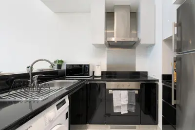 a kitchen with black counters and a sink at Gala Guests - Deluxe Marina View Apartments with Infinity Pool in Dubai